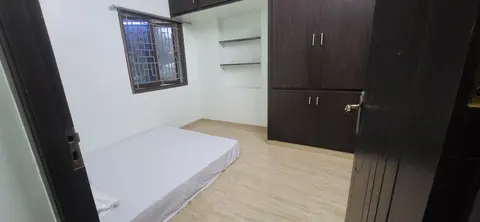 Second bedroom seen from the door, with a floor mattress, wardrobe and wall shelves