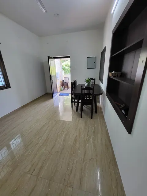 Living hall with a wooden dining table and chairs, and the open door to the porch