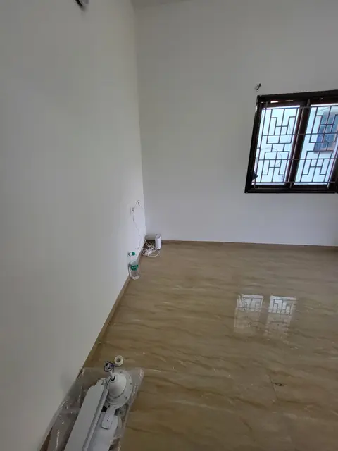 Corner of the living hall with a grilled window and tiled floor
