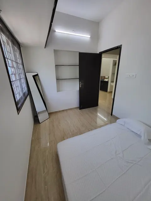 Floor mattress in the second bedroom, with wall shelves and the door to the hall