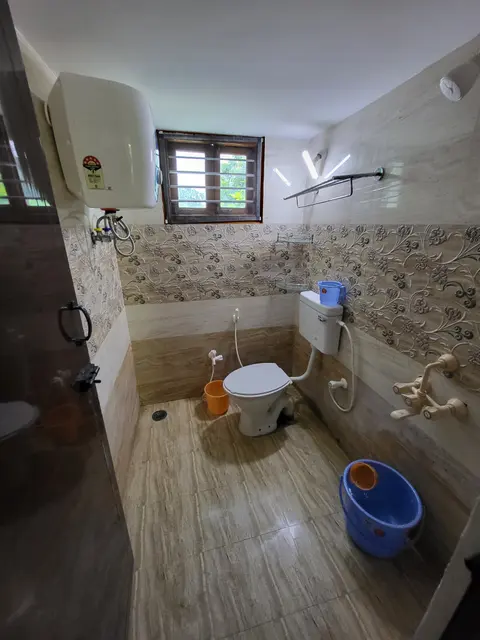 Toilet with a western WC, wall-mounted water heater, towel rail and patterned tiles